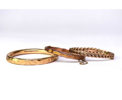 A 9ct rose gold hinged bangle, together with a 9ct yellow gold hollow bangle (at fault) and a yellow metal hinged bangle (cla