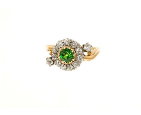 Late Victorian green garnet and diamond cluster ring with a round mixed cut green garnet surrounded by a border of eleven old