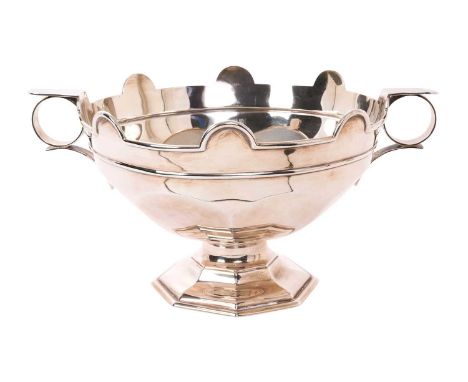 Early George V Art Deco style silver punch bowl of faceted form, with twin handles and a crenelated rim, on an octagonal pede