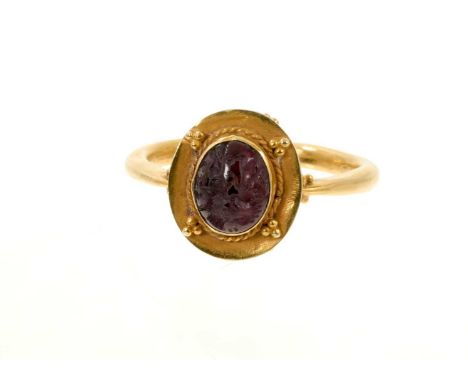 Antique Roman style ring with an intaglio carved garnet in a rub over setting on a gold oval mount on a gold shank, ring size