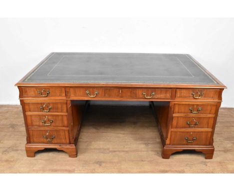 Twin pedestal partners' desk with green leather top and nine drawers about the kneehole, the reverse with cupboards to the pe