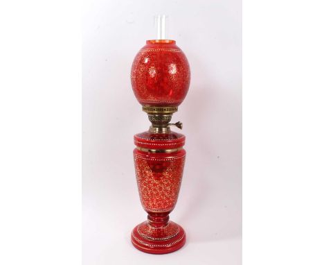 Victorian cranberry glass oil lamp with matching shade, decorated in enamels and gilt with foliate patterns and beading, 59cm