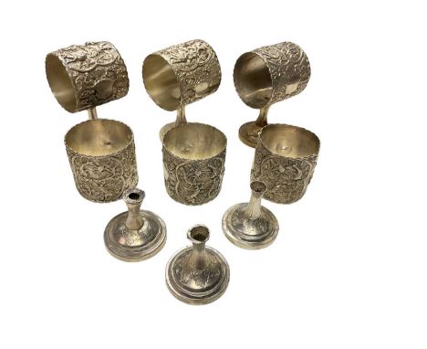 Six Far Eastern white metal napkin rings, with rural and undersea decoration, on pedestal bases, unmarked (Some pedestals det