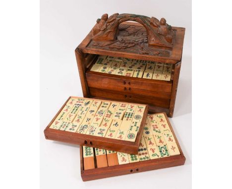 Antique Chinese bone and bamboo mahjong set, housed in five drawers within relief carved wooden case with surmounting carved 