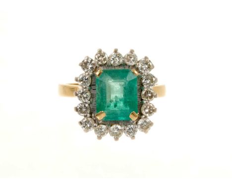 Emerald and diamond cluster ring with a rectangular step cut emerald measuring approximately 9.25 x 7.4 x 4.75mm, surrounded 