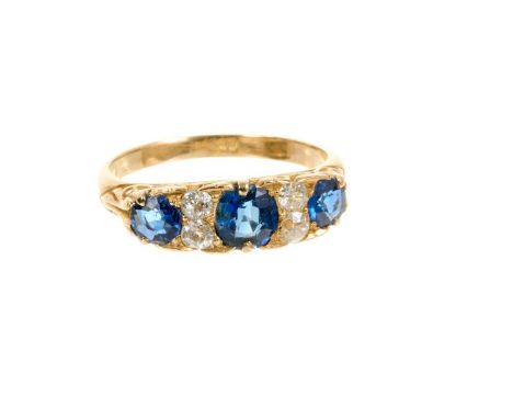 Antique sapphire and diamond ring with three round mixed cut blue sapphires and four old cut diamonds in carved gold claw set
