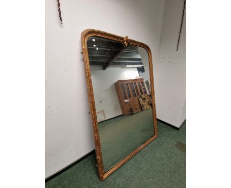 A VICTORIAN RECTANGULAR MIRROR WITH A ROUNDED TOP AND WITHIN A BEADED AND FOLIATE GILT FRAME CRESTED BY A LEAF BRACKET.   218