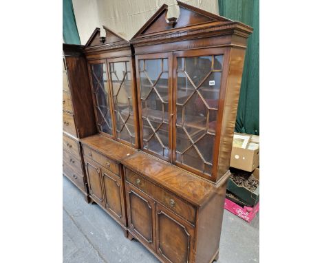 A PAIR OF MODERN MAHOGANY DISPLAY CABINETS, EACH WITH A BROKEN PEDIMENT ABOVE GLAZED DOORS ENCLOSING SHELVES AND RECESSED ABO
