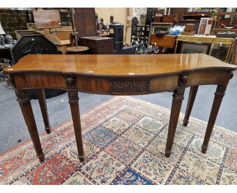 AN ADAM STYLE MAHOGANY SERVING TABLE, CENTRE OF THE SERPENTINE APRON WITH A CARVED PANEL OF TWO EAGLE HEADS AND FLOWERS, RAMS