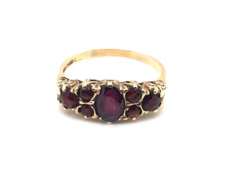 A 9ct HALLMARKED GOLD SEVEN STONE GARNET CARVED HALF HOOP RING. FINGER SIZE R 1/2. WEIGHT 2.90grms.