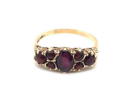 A 9ct HALLMARKED GOLD SEVEN STONE GARNET CARVED HALF HOOP RING. FINGER SIZE R 1/2. WEIGHT 2.90grms.