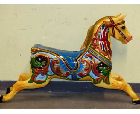 A VINTAGE FIBRE GLASS FAIR GROUND  CAROUSEL HORSE PAINTED WITH UNION FLAGS ON ITS YELLOW NECK AND WITH A BLUE SADDLE BEHIND. 