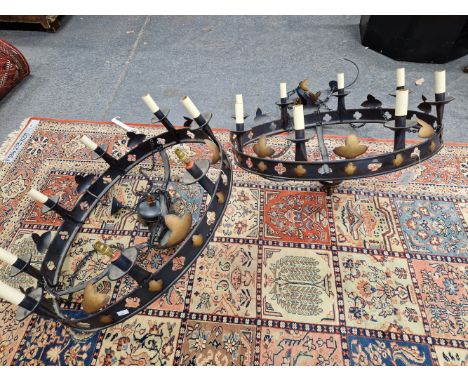 A PAIR OF EIGHT LIGHT CHANDELIERS, EACH FORMED OF A BLACK METAL RING ALTERNATIVELY PIERCED AND GILT WITH QUATREFOILS, THE THR