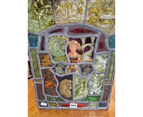 A LEADED GLASS PANEL WORKED WITH A STYLISED ARMORIAL BELOW THREE PANELS OF FIGURES.   44 x 31cms