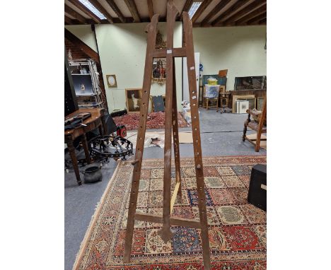 A LATE VICTORIAN PINE EASEL, THE SCREW IN PEG PICTURE RESTS ADJUSTABLE TO ELEVEN&nbsp; HOLES, THE CENTRAL UPRIGHT WITH TREFOI
