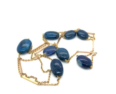 A CONTINUOUS STAND OF BLUE HARD STONE BEADS WITH BAR AND LINK CHAIN. LENGTH APPROX 70cms, UNHALLMARKED, ASSESSED AS 9ct GOLD,