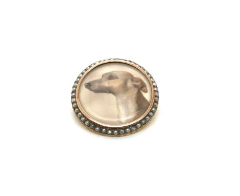 AN ANTIQUE PAINTED UNSIGNED PORTRAIT MINIATURE OF A DOG, HELD IN A BROOCH MOUNT WITH A SEED PEARL FRAME. UNHALLMARKED, ASSESS