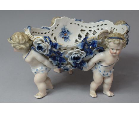 A Continental Blue, White and Coloured Enamel Table Centre, Reticulated Bowl Supported by Four Cherubs, 30cm wide 