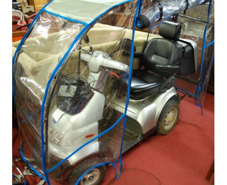 A TGA battery powered mobility scooter, with integral storage trunk, perspex rain cover, battery charger and keys