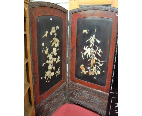 An early 20th century Japanese floral relief carved framed two division dressing screen, each inset with red and black lacque