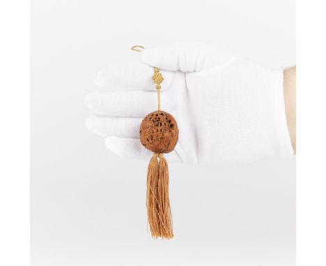 A Chinese 20th century carved walnut pendant with a thread tied into a treasure knot and tassels. Carving includes an array o
