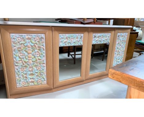 A large modern light wood sideboard with four doors to the front, two mirrors to the center and carved coloured panels&nbsp; 