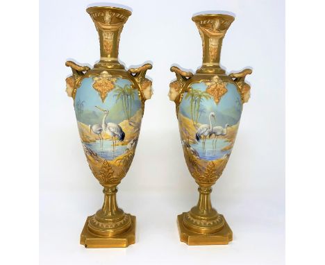 A pair of Royal Worcester balluster vases with ornate gilt neck, facemask mounts decorated with cranes in exotic landscapes, 