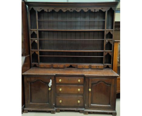 An 18th Century oak dresser with reverse breakfront, the later high raised back with moulded cornice, pierced and fretted fri