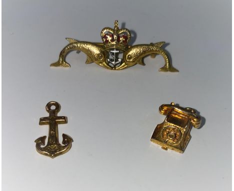 A Submariner's lapel badge in 9 carat hallmarked gold and enamel; a 9 carat hallmarked telephone charm; an anchor charm, unma