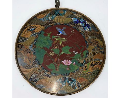 A late 19th/early 20th century Japanese cloisonné circular wall plaque, the central panel with finely detailed blue bird flyi