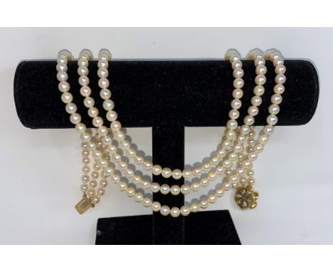 A cultured pearl necklace, triple strand with yellow metal circular flower head clasp set 6 garnets and central pearl, a pair