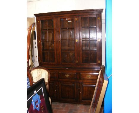 An oak bookcase in the Georgian style with glazed upper section and drawers and cupboards below