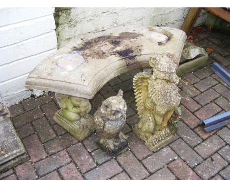 A curved concrete garden bench, together with an owl and a griffin ornament