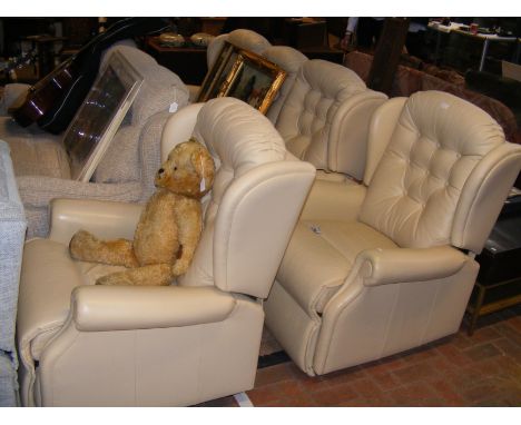 A living room suite comprising a three seater sofa and two armchairs, upholstered in cream leather and all with electric recl