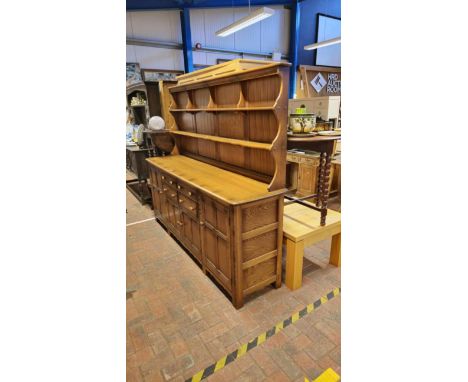 A large dark wood Ercol dresser, comprising utility cupboards and drawers below and plate rack to back - width approx. 215cm 