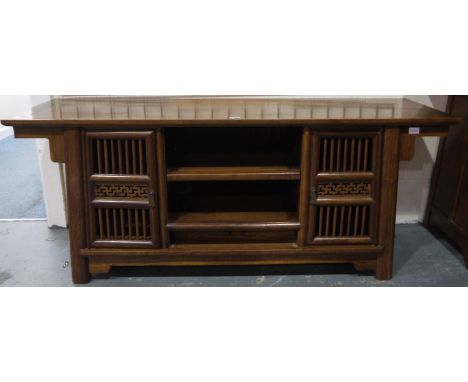 A 20th century hardwood media stand in the Oriental manner, having two shelves flanked by pierced cupboard doors, 160 x 50 x 