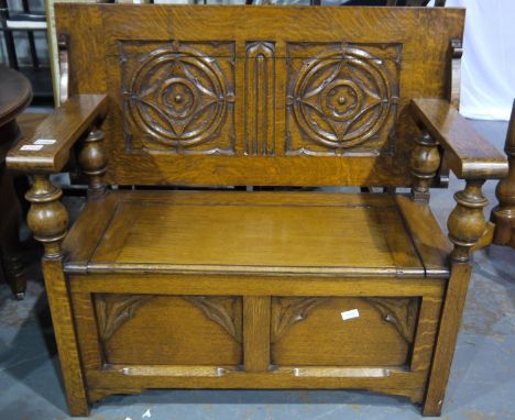 An early 20th century oak monks bench, the hinged top with carved decoration and the box-seat panelled, L: 154 cm, split to b