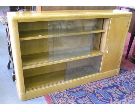 A LIGHT OAK BOOKCASE WITH PLATE GLASS SLIDING DOORS
