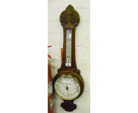 AN EDWARDIAN CARVED OAK ANEROID BAROMETER WITH THERMOMETER