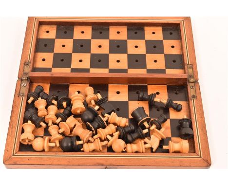 An Edwardian travelling chess set, the turned wooden pieces fitted inside a pegged chess board which is revealed when box is 