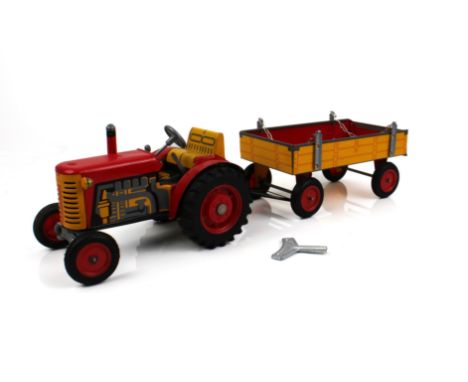 A clockwork tinplate toy tractor and trailer by Zetor - late 20th century, in red and yellow with working steering and three 