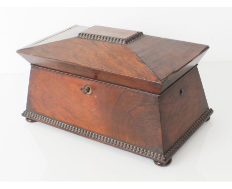 A large late-Regency rosewood tea caddy: of sarcophagus form, with reel moulded borders and bun feet, the interior with twin 