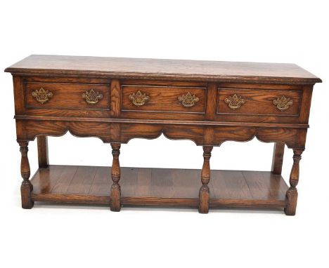 Late 20th-century reproduction Montgomeryshire design oak dresser base, three drawers with fretwork brass handles, four balus