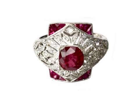 RUBY, SPINEL AND DIAMOND RING, the central ruby set to an openwork diamond set border, with calibre cut diamonds to each corn