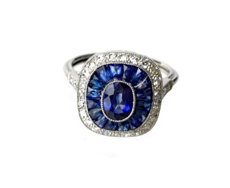 SAPPHIRE AND DIAMOND RING, the central oval sapphire bordered by calibre cut sapphires and round brilliant cut diamonds, unma