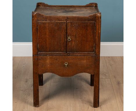 A George III mahogany bedside commode, the tray top over a pair of cupboard doors with commode drawer below, raised on square