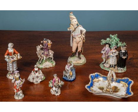 A collection of Derby figural groups to include a pig tithe group; a tailor riding a goat; together with a porcelain figure o