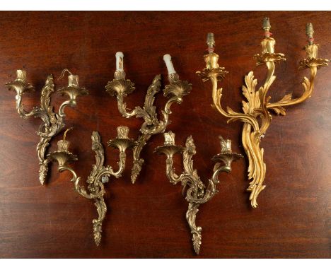 A set of four two-light brass wall brackets of foliate design in arabesque form; together with another similar gilt metal thr