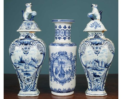 A pair of Dutch Delft tin-glazed vases of rectangular baluster form, the lids decorated with lions; together with a cylindric