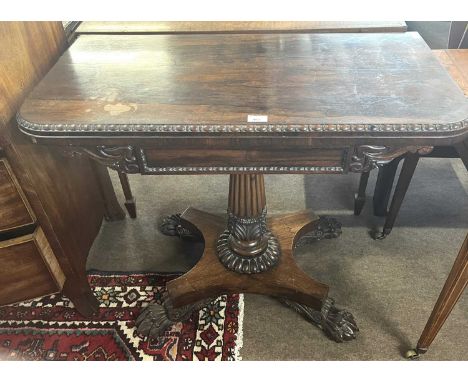 An early 19th Century rosewood card table, the top with red baize lining set on a fluted column with platform base and carved